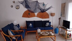 A living room with a sofa, two armchairs, a coffee table, and a TV stand. - Costa Serena, cottage near the sea. (Palau)