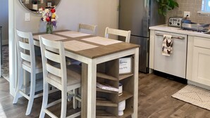 Una cocina moderna con una mesa de comedor, sillas, un refrigerador y un espejo.
