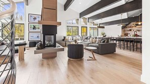 Amplia sala de estar con chimenea, escalera y zona de cocina con asientos tipo barra.