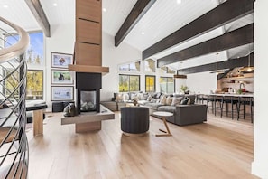 A spacious living area with a fireplace, a staircase, and a kitchen area with bar seating.