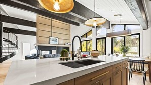 Una cocina moderna con una isla grande, armarios empotrados e iluminación colgante.