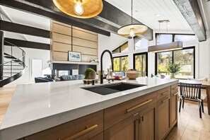 A modern kitchen with a large island, built-in cabinets, and pendant lighting.