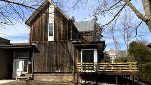 A rustic wooden building with a sloped roof, a front door, and a small porch with a bench. - BEACHVIEW GETAWAY (Sheboygan)