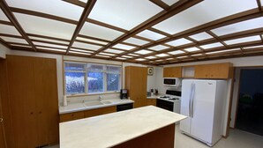 A compact kitchen with a central island, wooden cabinets, a microwave, a stove, and a refrigerator. - BEACHVIEW GETAWAY (Sheboygan)