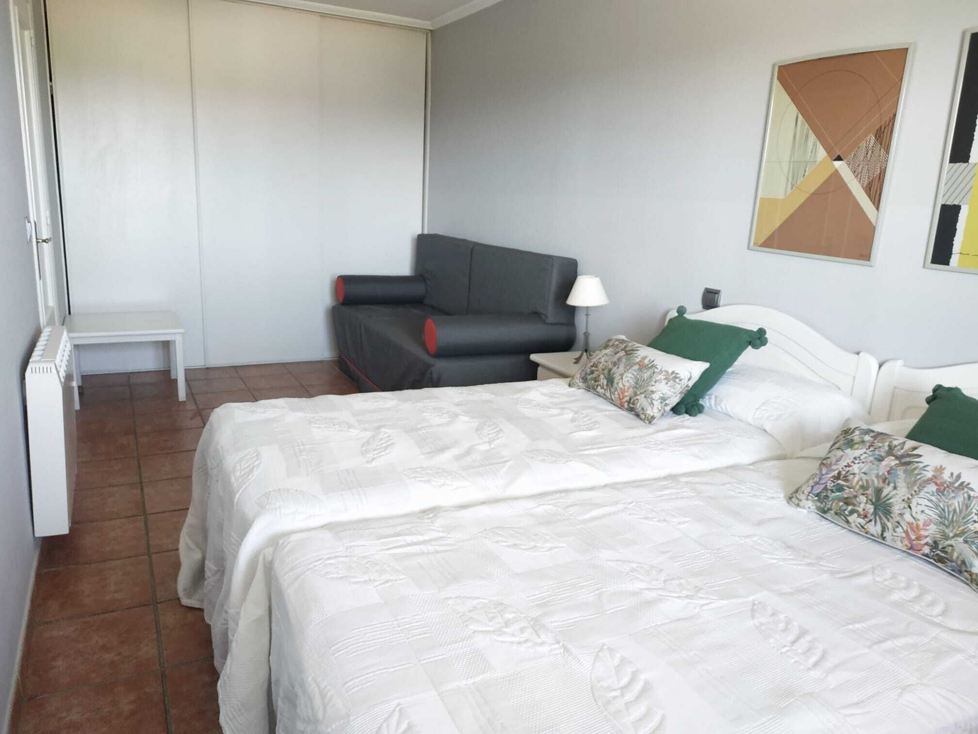 A hotel room with a bed, a chair, a small table, and a wardrobe.