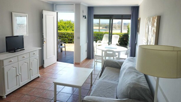Un salon moderne avec un canapé, un téléviseur posé sur un meuble, une table et un balcon offrant une vue agréable.