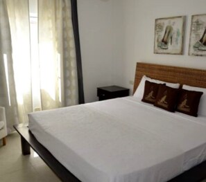 Relax in this serene space with a large bed, wall-mounted artwork, and a convenient nightstand.