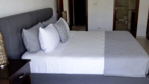 Een slaapkamer met een bed, een nachtkastje en een deur naar een andere kamer.