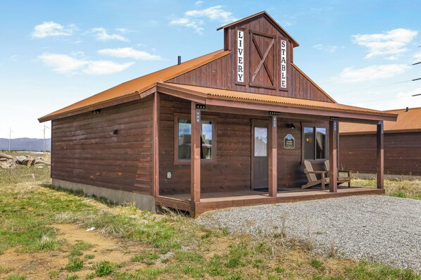 A wooden building with a covered porch and a sign reading 'LIVERY STABLE'.