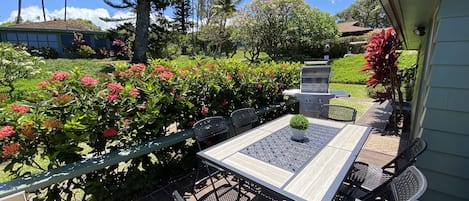 En uteplats med ett bord och stolar, omgiven av frodig grönska och blommande växter.