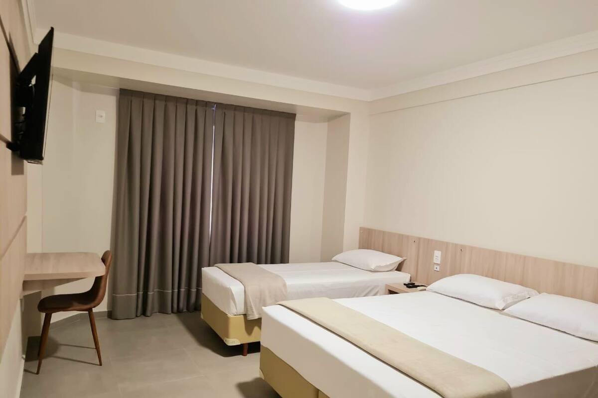 A hotel room with two beds, a desk, and a chair.
