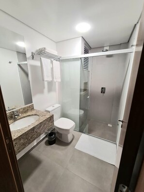 A modern bathroom with a glass-enclosed shower, a marble sink, and a toilet. - HOTEL MERAKI (Lebon Régis)