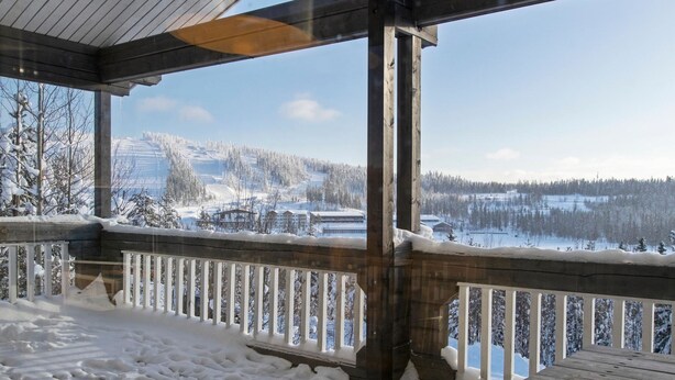 A wooden deck with a railing overlooking a snowy landscape with buildings and trees. - Hallan paroni b paritalo by Interhome (Hyrynsalmi)
