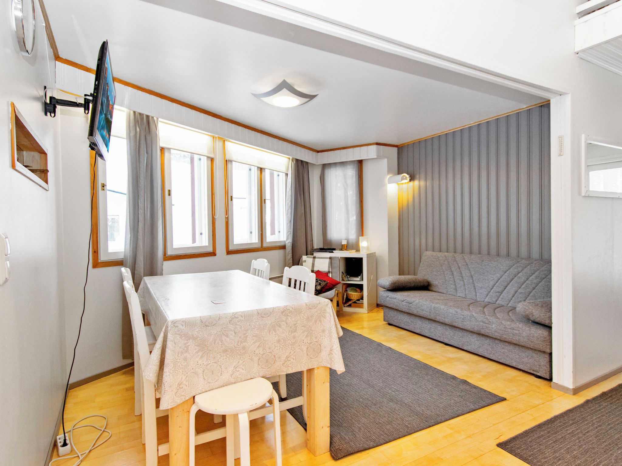 Un salon moderne avec une table à manger, un canapé et un téléviseur fixé au mur.