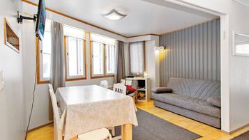 Un salon moderne avec une table à manger, un canapé et un téléviseur fixé au mur.