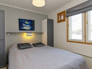 A bedroom with a bed, a painting, a window, and a door.