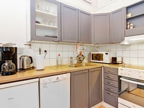 A compact kitchen with grey cabinets, a microwave, a coffee maker, and a dishwasher.