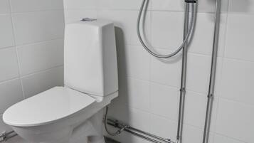 A modern bathroom with a toilet, a shower, and a wall-mounted faucet.