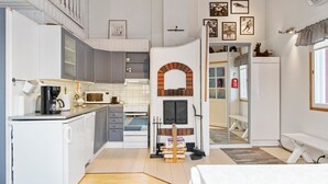 A compact kitchen with a microwave, coffee maker, and a small oven. There is a wooden bench and a bed in the room.