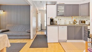 A compact, modern apartment with a kitchenette, a dining area, and a living room with a sofa.