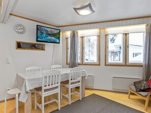 A dining area with a table, chairs, a television, and a window with curtains. - Hallantytär b3 paritalo by Interhome (Hyrynsalmi)