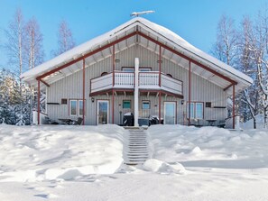 Un edificio de dos pisos con un balcón, rodeado de nieve.