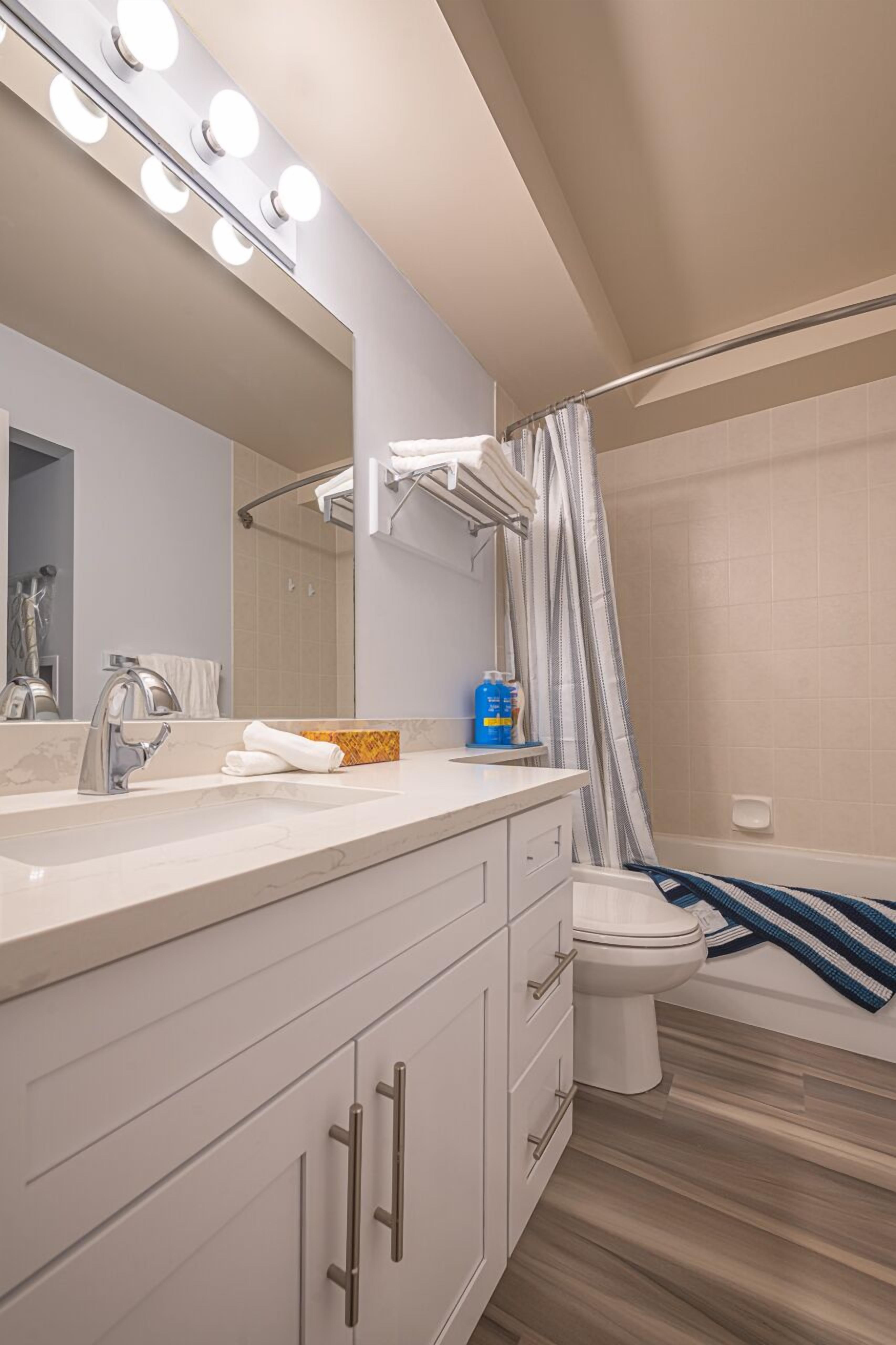 A modern bathroom with a vanity, mirror, and shower curtain.