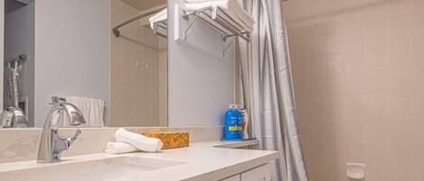 A modern bathroom with a vanity, mirror, and shower curtain.
