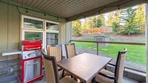 Un patio techado con una parrilla, una mesa y sillas.