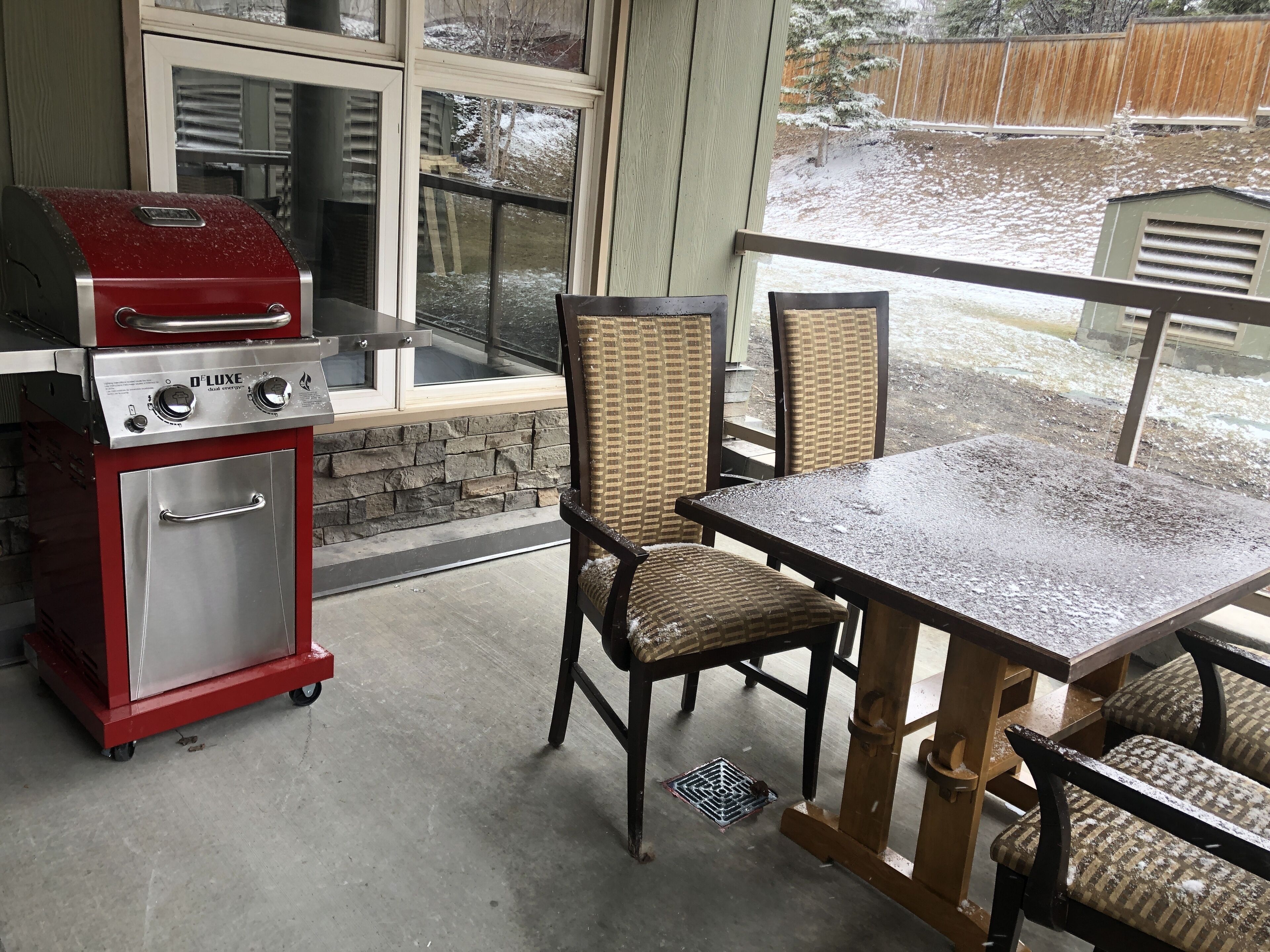 Une terrasse extérieure couverte, équipée d’un barbecue, de chaises et d’une table.