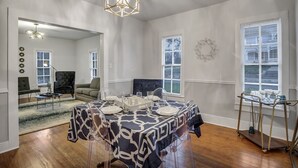 Une salle à manger avec une table dressée pour quatre personnes, un lustre et une vue sur le salon.