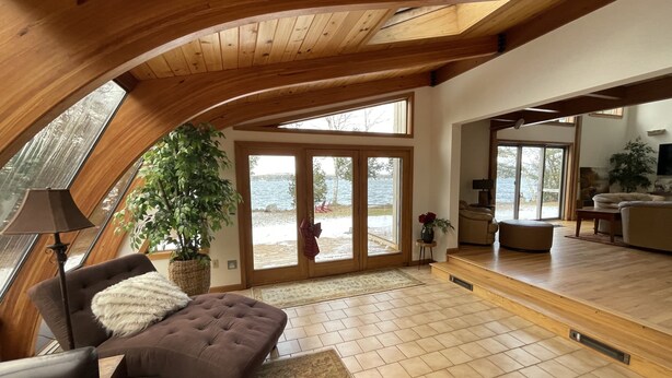 A spacious living area with a high ceiling, large windows, and a view of the outdoors. - Stunning Private Lakehouse with Dock and outdoor Hot Tub (Manchester)