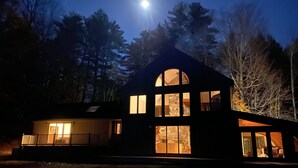 A two-story house with large windows and a visible interior. - Stunning Private Lakehouse with Dock and outdoor Hot Tub (Manchester)