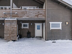 A two-story building with a wooden exterior, a front door, and a small window.