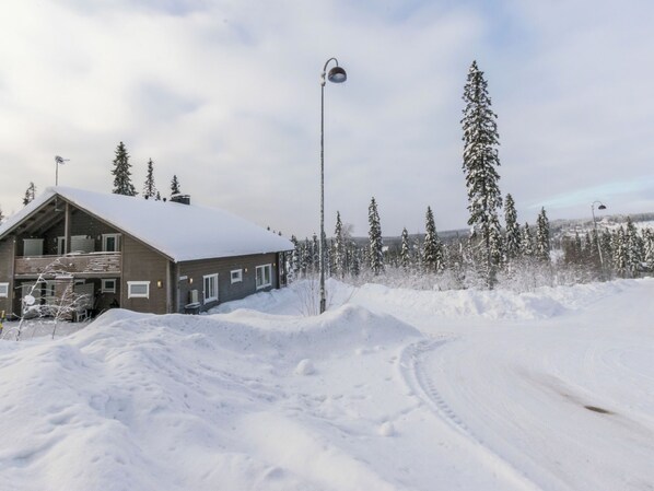 A snow-covered landscape with a building featuring a balcony and a street lamp.