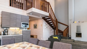 A modern interior with a dining area, kitchen, and a staircase leading to an upper level.