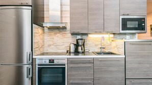 A modern kitchen with stainless steel appliances, wooden cabinets, and a stone backsplash.