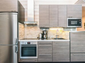 Een moderne keuken met roestvrijstalen apparatuur, houten kastjes en een betegelde achterwand.