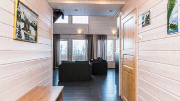 Un pasillo con paredes de madera, un banco, un sofá y una puerta que da a otra habitación.