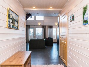 A hallway with wooden walls, a bench, a sofa, and a door leading to another room.