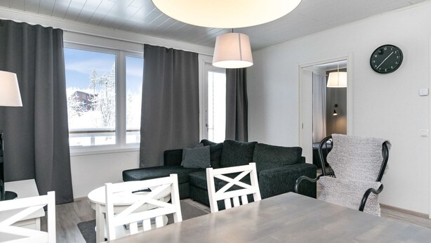 Una sala moderna con un sofá, sillas, una mesa de comedor e iluminación colgante grande.
