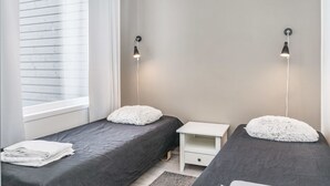 Un dormitorio con dos camas, una ventana y una mesita de noche.