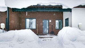 Una casa cubierta de nieve con fachada de ladrillo, una puerta principal y un buzón visible.