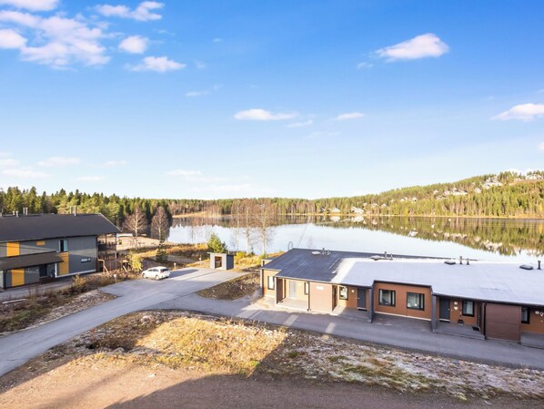 A lakeside property with modern buildings, a clear sky, and a calm lake.