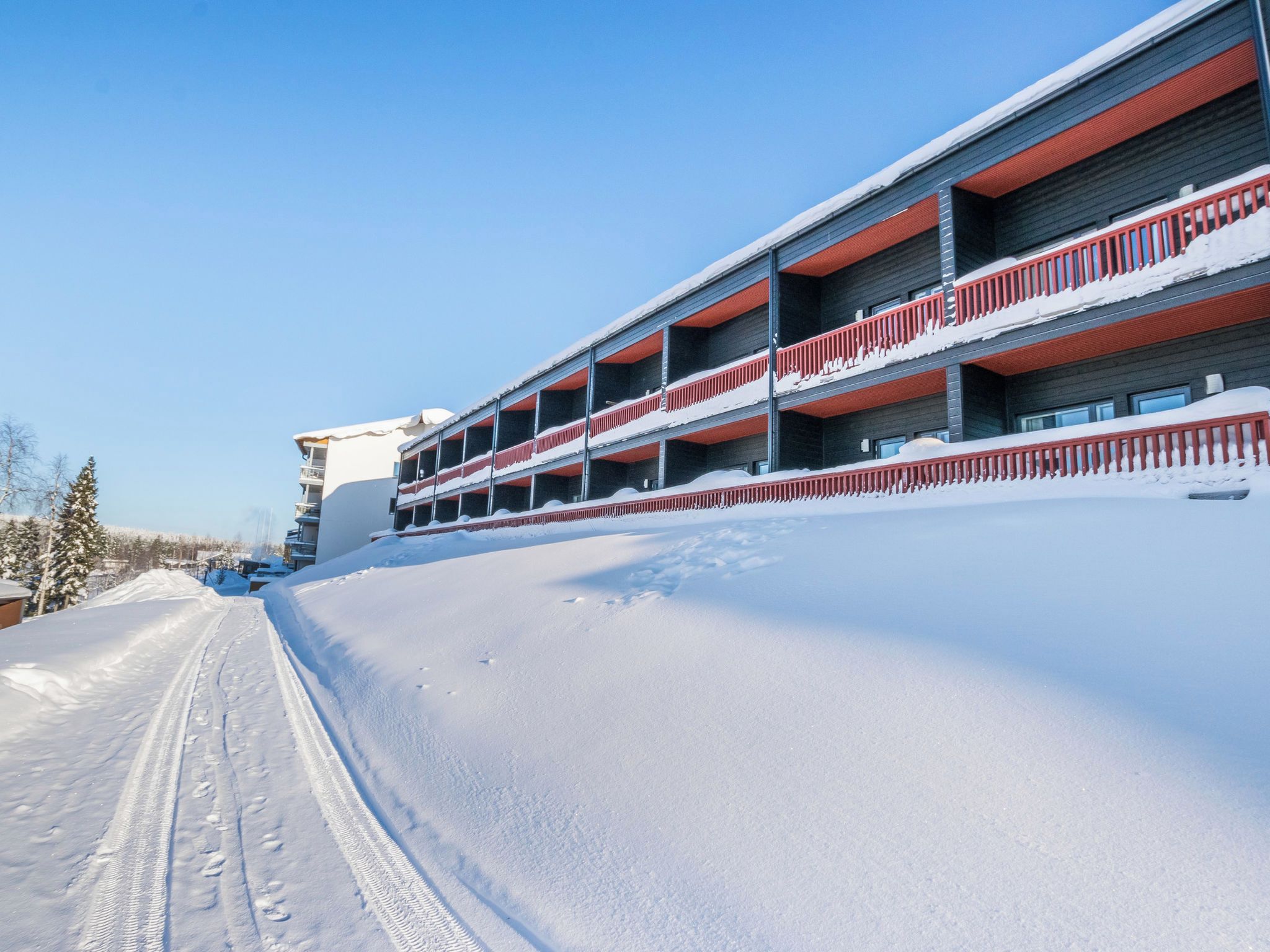 A multi-story building with balconies, surrounded by snow-covered ground.