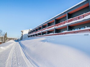 A multi-story building with balconies, surrounded by snow-covered ground.