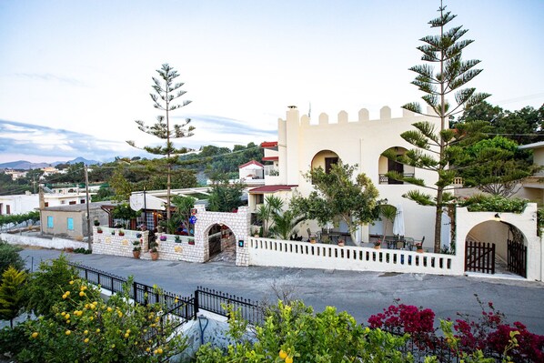 A building with a castle-like facade, a paved entrance, and surrounding greenery.