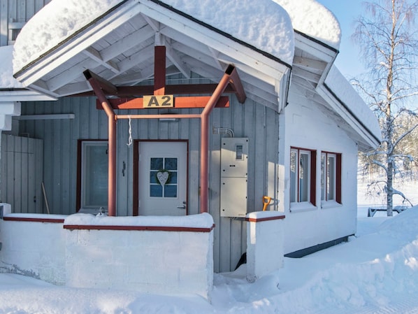A snow-covered building with a wooden porch, a door with a heart-shaped decoration, and a sign labeled 'A2'.