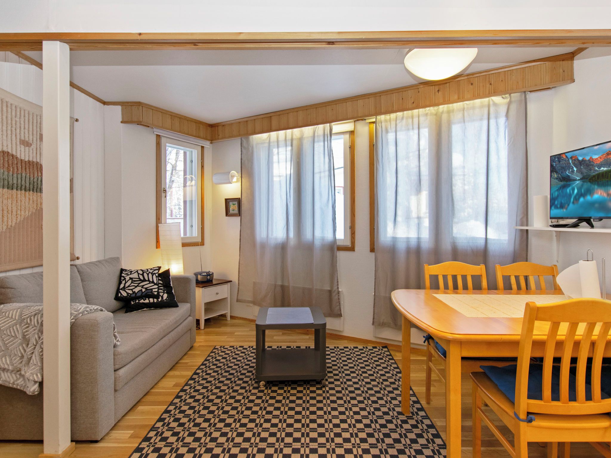 Un salon confortable avec un canapé, une petite table, une table à manger avec des chaises et un téléviseur.