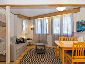 A cozy living room with a sofa, a small table, a dining table with chairs, and a television. - Hallantytär a2 paritalo by Interhome (Hyrynsalmi)
